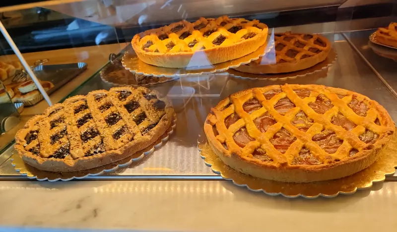 Crostate con la grata di pasta frolla, alla marmellata e alla confettura scura, nella vetrina sopra il marmo